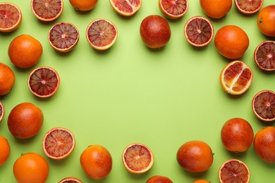 Frame of ripe sicilian oranges on light green background, flat lay. Space for text