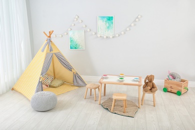 Photo of Cozy kids room interior with table, play tent and toys
