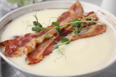 Photo of Delicious potato soup with bacon and microgreens on table, closeup