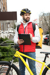 Courier with thermo bag and clipboard on city street. Food delivery service