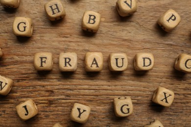 Word Fraud of cubes with letters on wooden background, flat lay