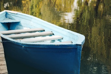 Light blue wooden boat on lake near pier