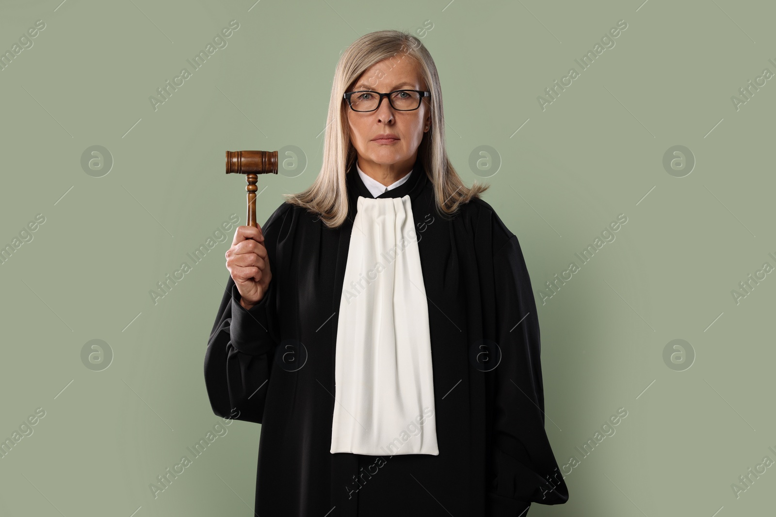 Photo of Senior judge with gavel on green background