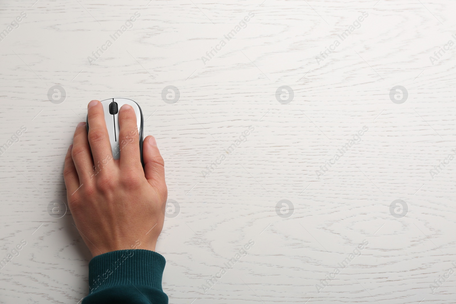 Photo of Man using computer mouse on wooden table, top view. Space for text