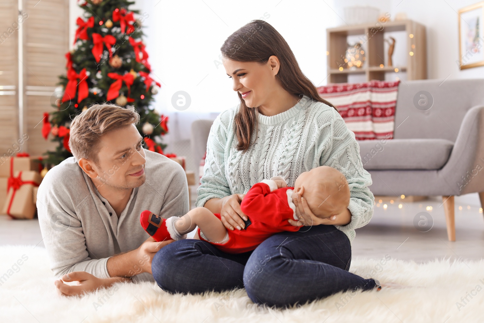 Photo of Happy couple with baby celebrating Christmas together at home