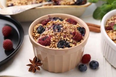 Photo of Tasty baked oatmeal with berries and anise star on white table, closeup