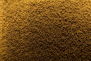 Many gold beads as background, view through glass