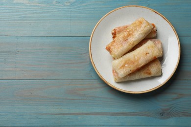 Photo of Delicious fried spring rolls on light blue wooden table, top view. Space for text