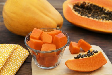 Photo of Tasty whole and cut papaya fruits on wooden table, closeup