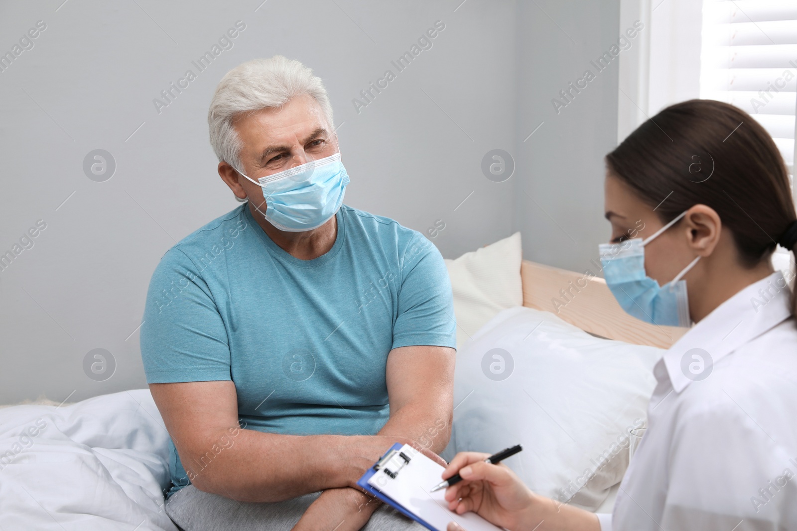 Photo of Doctor examining senior man with protective mask at nursing home