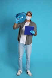 Photo of Courier in medical mask with bottle for water cooler and clipboard on light blue background. Delivery during coronavirus quarantine