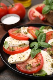 Plate of delicious Caprese salad with pesto sauce on table, closeup