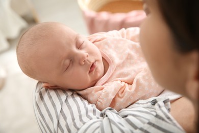 Photo of Mother holding her sleeping baby indoors, closeup