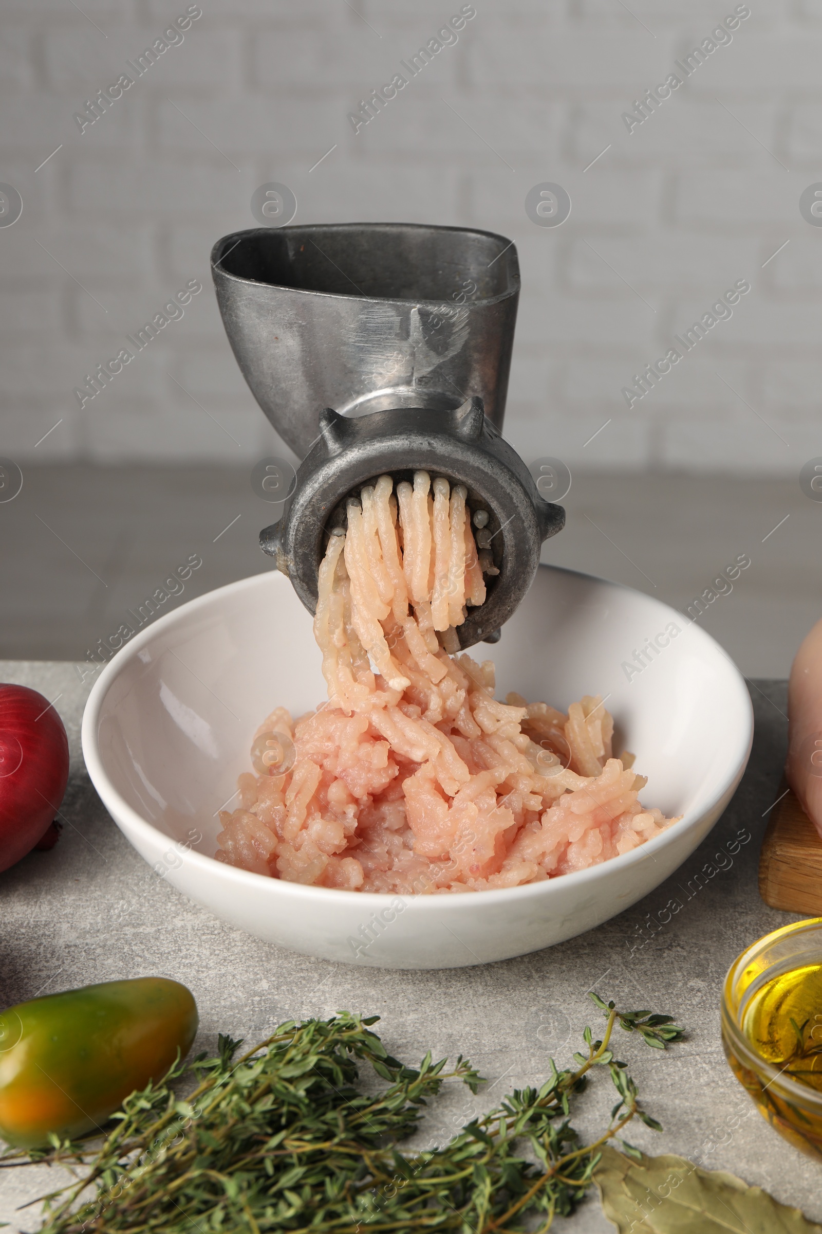 Photo of Metal meat grinder with chicken mince and different products on light grey table