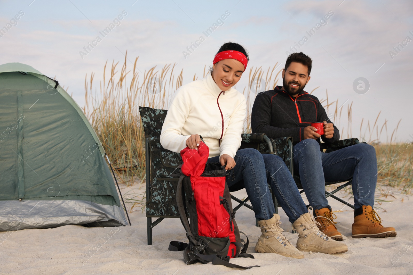 Photo of Couple resting near camping tent on beach