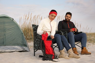 Couple resting near camping tent on beach