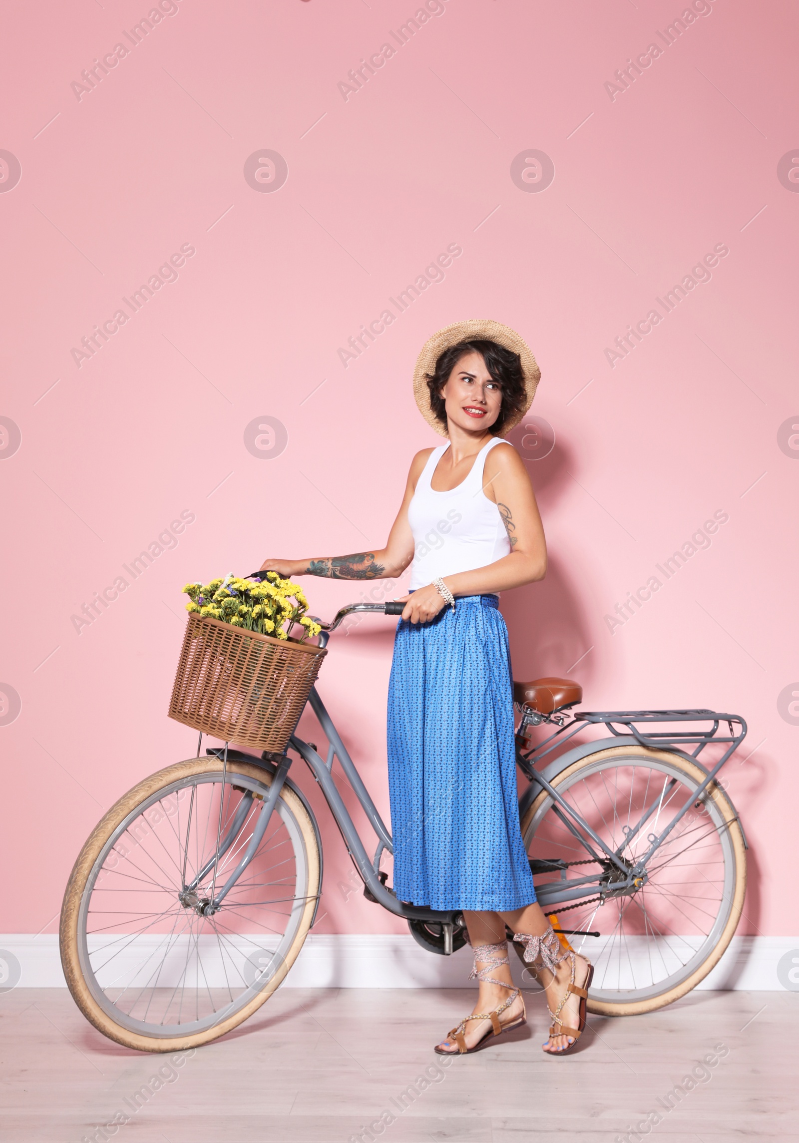 Photo of Portrait of beautiful young woman with bicycle near color wall