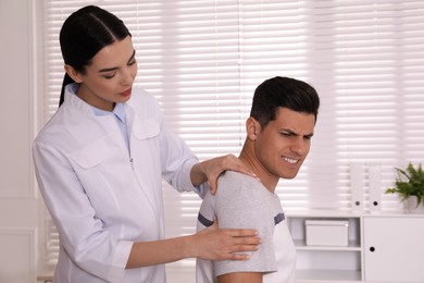 Photo of Doctor examining man with shoulder pain in hospital