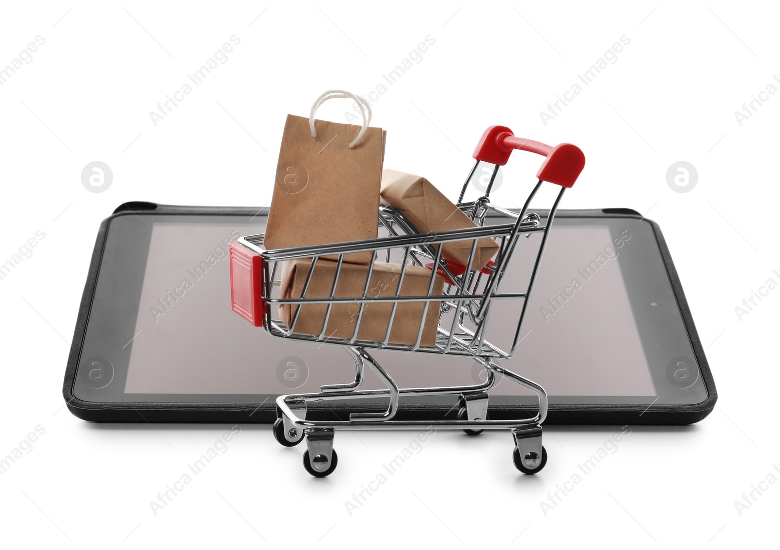 Photo of Internet shopping. Small cart with boxes and bag near modern tablet on white background