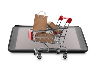 Internet shopping. Small cart with boxes and bag near modern tablet on white background