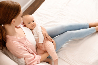 Young woman with her little baby resting after breast feeding on bed, above view