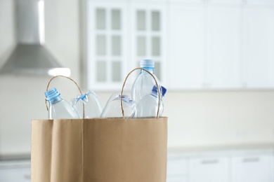 Photo of Paper bag with used plastic bottles in kitchen, space for text. Recycling problem