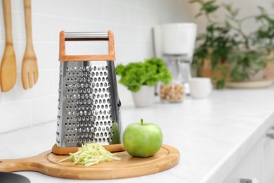 Photo of Grater and fresh ripe apple on kitchen counter. Space for text