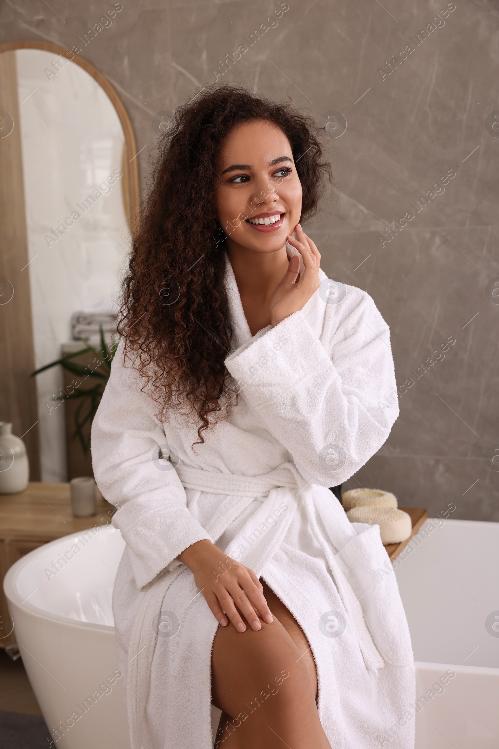 Photo of Beautiful African American woman sitting on edge of tub in bathroom