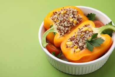 Photo of Quinoa stuffed bell pepper and parsley in bowl on green background, closeup. Space for text