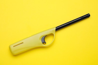 Photo of One gas lighter on yellow background, top view