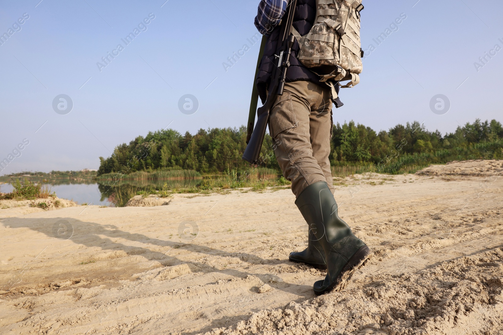 Photo of Man with hunting rifle and backpack outdoors, closeup. Space for text