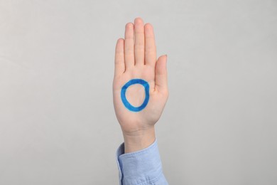 Woman showing blue circle drawn on palm against light grey background, closeup. World Diabetes Day