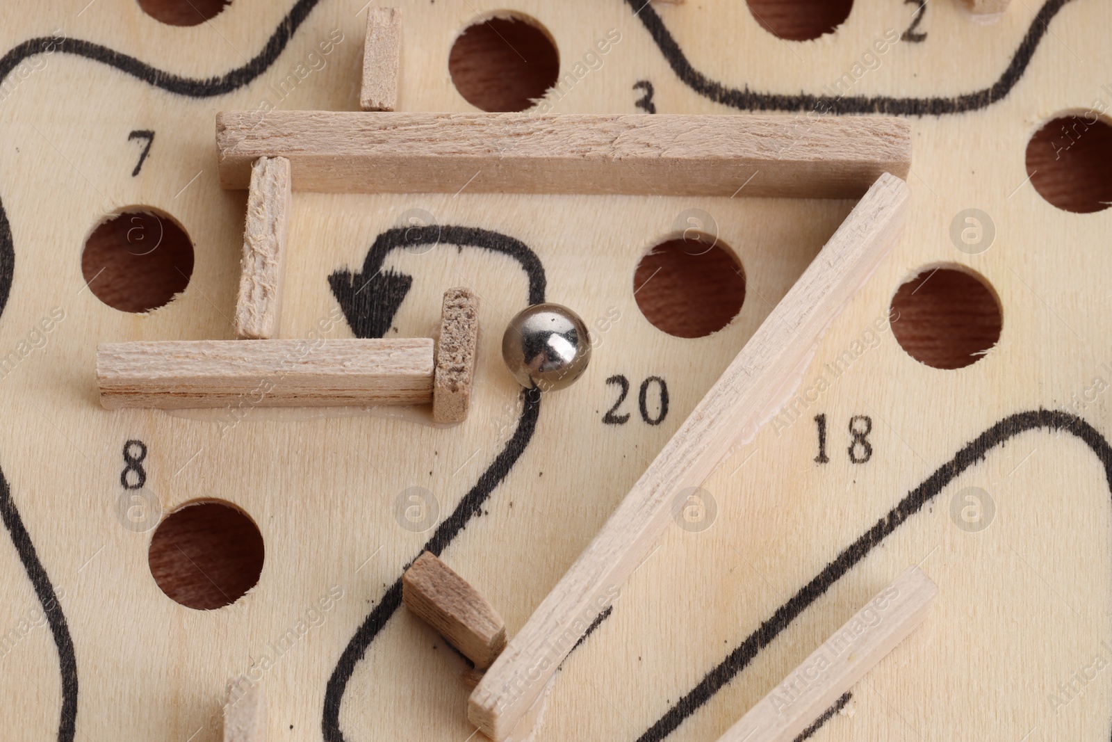 Photo of Wooden toy maze with metal ball, above view