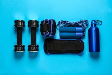 Photo of Weighting agents and sport equipment on light blue background, flat lay