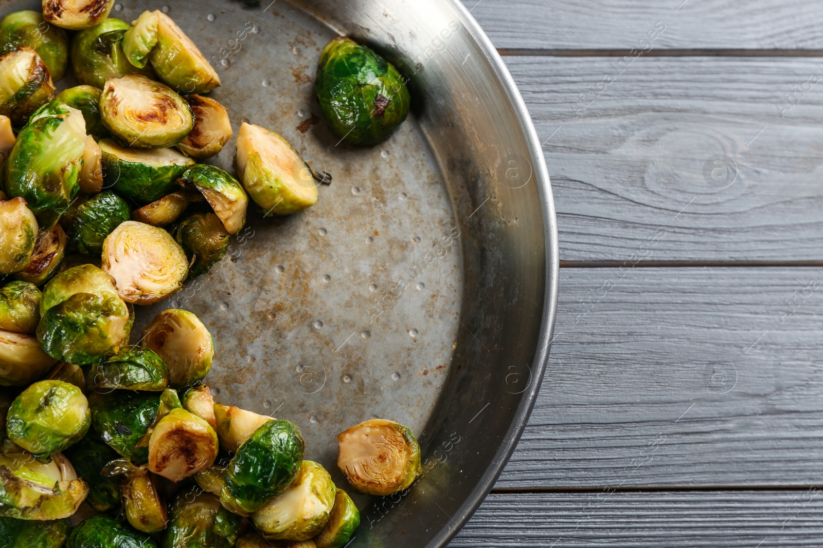 Photo of Delicious roasted brussels sprouts on grey wooden table, top view. Space for text