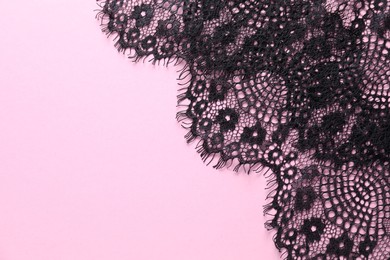 Photo of Black lace on pink background, top view. Space for text