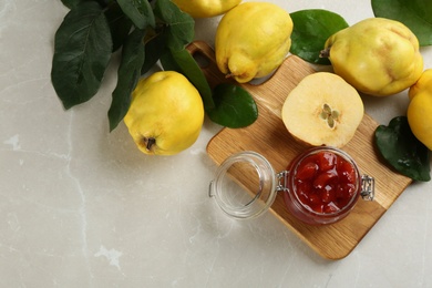 Photo of Delicious quince jam and fruits on light grey marble table, flat lay. Space for text