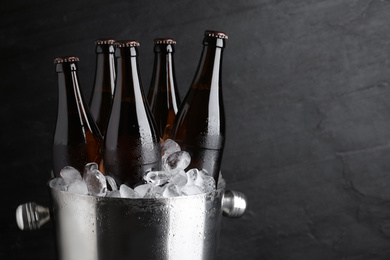 Photo of Metal bucket with beer and ice cubes on black background, closeup. Space for text