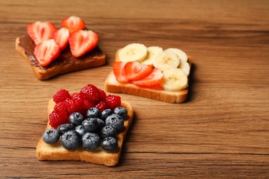 Tasty toasts with different spreads and fruits on wooden table. Space for text