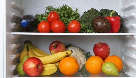 Photo of Open refrigerator with many different fresh vegetables and fruits