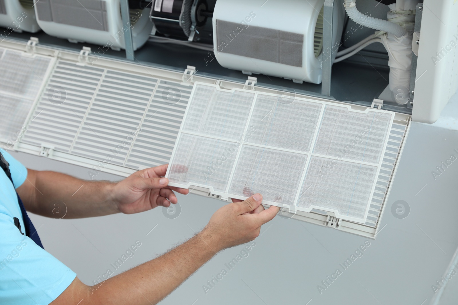 Photo of Male technician cleaning air conditioner indoors