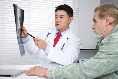 Doctor showing MRI images to senior patient in hospital