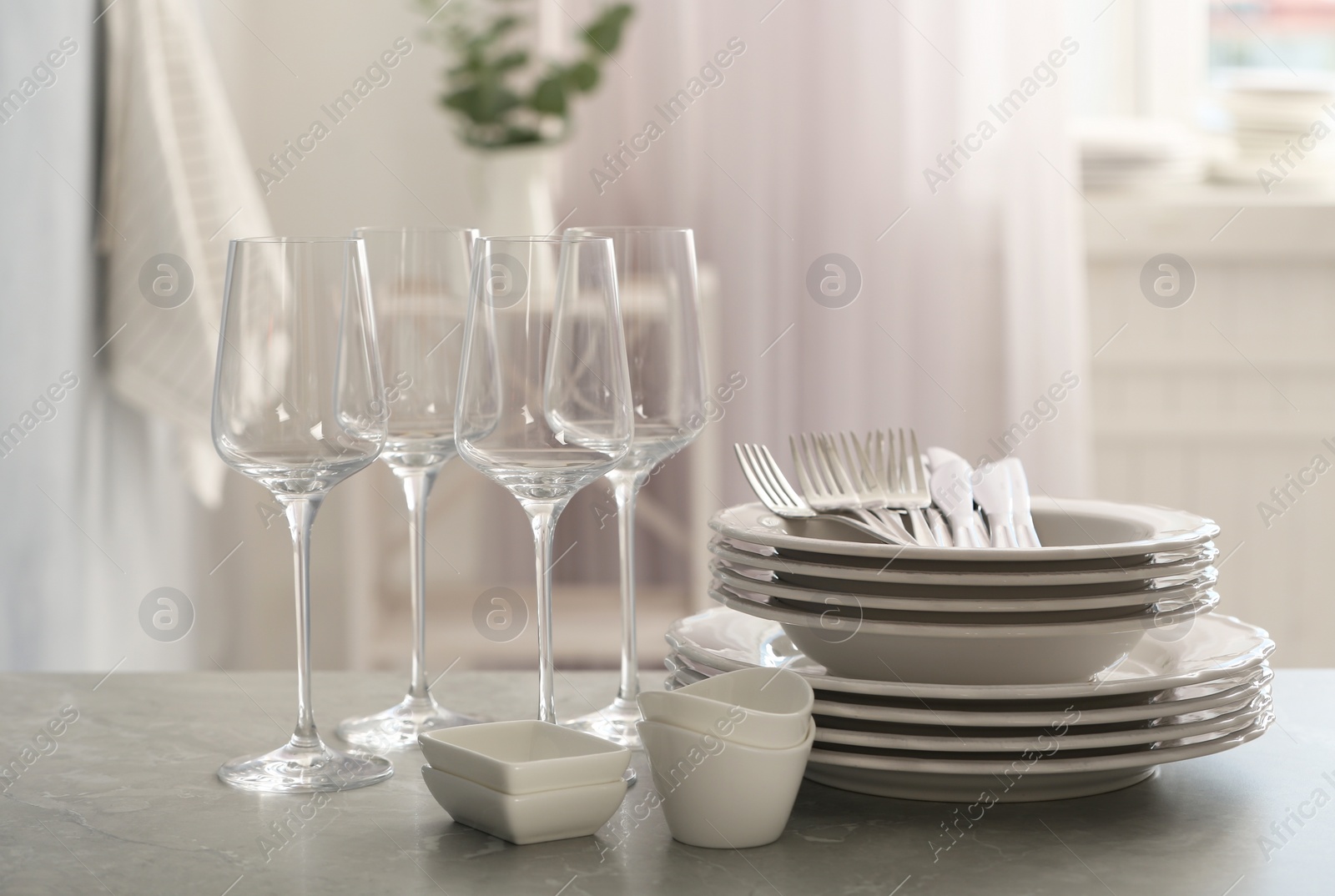 Photo of Set of clean dishware, cutlery and wineglasses on grey table indoors
