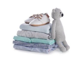 Photo of Stack of clean baby's clothes, toy and small shoes on white background