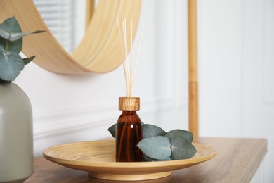 Reed diffuser and home decor on wooden table in room