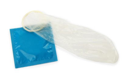 Photo of Unrolled condom and package on white background, top view. Safe sex