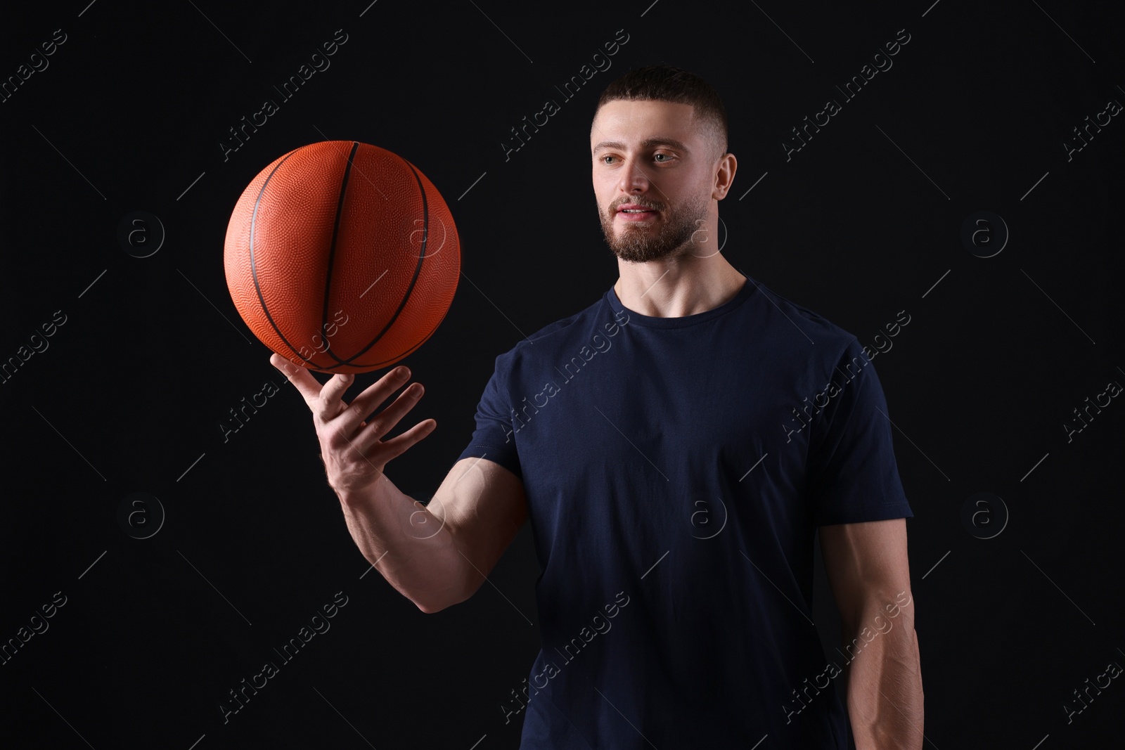 Photo of Athletic young man with basketball ball on black background