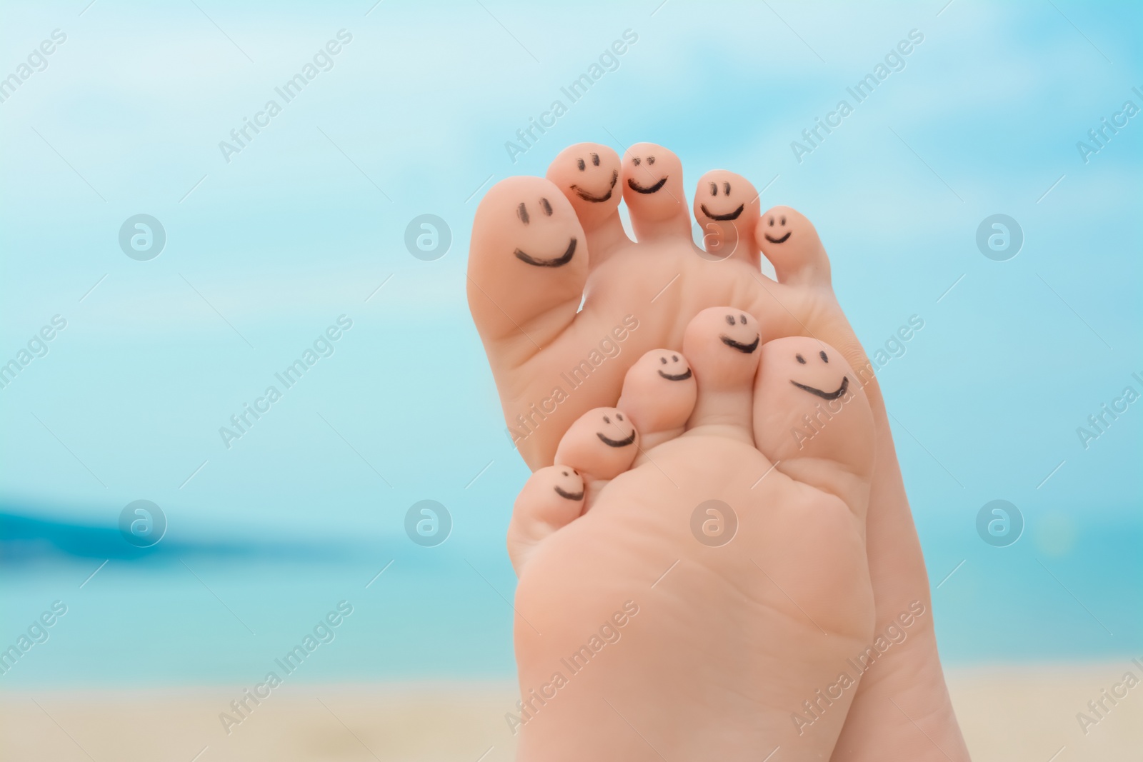 Photo of Woman with smiling faces drawn on toes outdoors, closeup of feet. Space for text