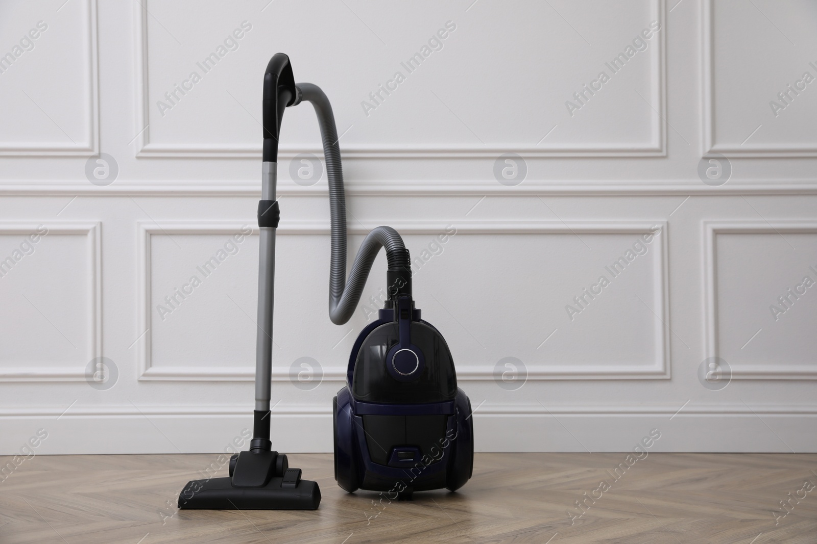 Photo of Modern vacuum cleaner near white wall indoors