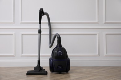 Photo of Modern vacuum cleaner near white wall indoors